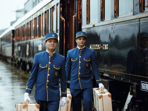 Venice Simplon-Orient-Express at the platform, two stewards in blue uniforms carrying the luggage | © Belmond