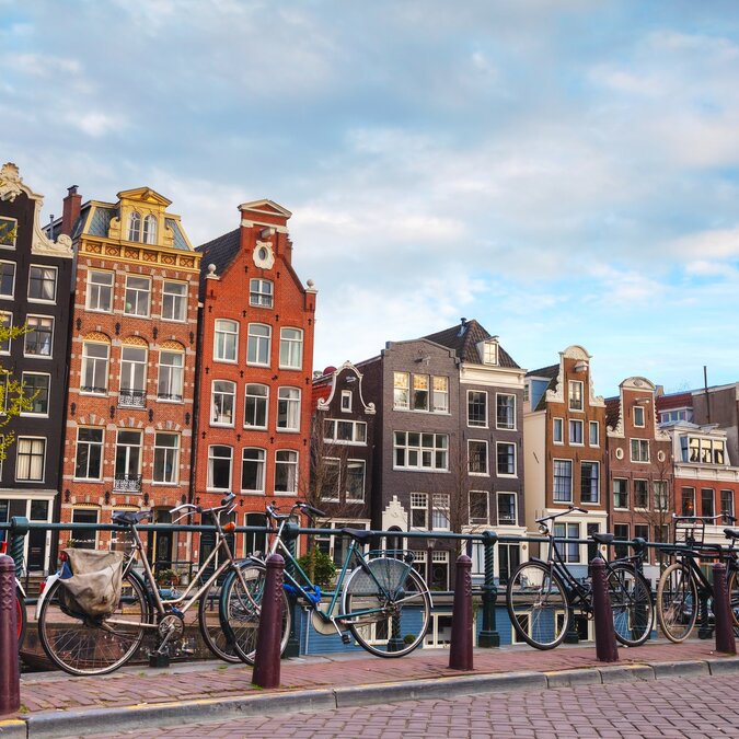Bicycles on a bridge with typical Amsterdam canal houses in the background. | © shutterstock 279532535