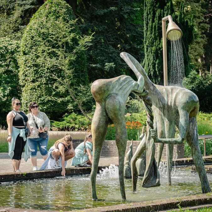 Modern fountain sculpture in Middelheim Sculpture Park, surrounded by visitors and green parkland. | © Tom Cornille – Middelheim Museum, Antwerp