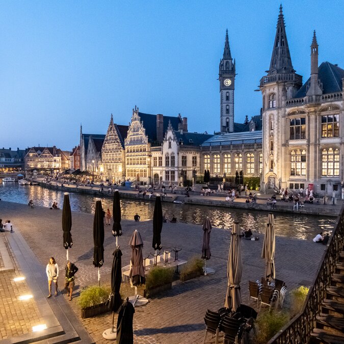 Evening view of the illuminated guild houses on the Graslei in Ghent with the riverbank and people. | © Bas van Oort – Ghent, view of Graslei
