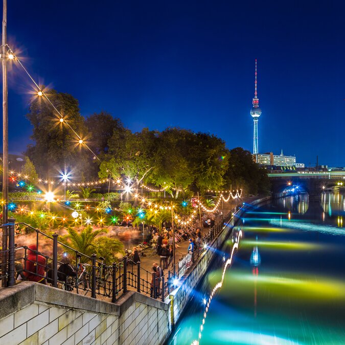 People dancing at summer beach bar beach party near Spree river on historic Museum Island with famous TV tower in the background during blue hour at night, Berlin Mitte district, Germany | © Shutterstock 377514604