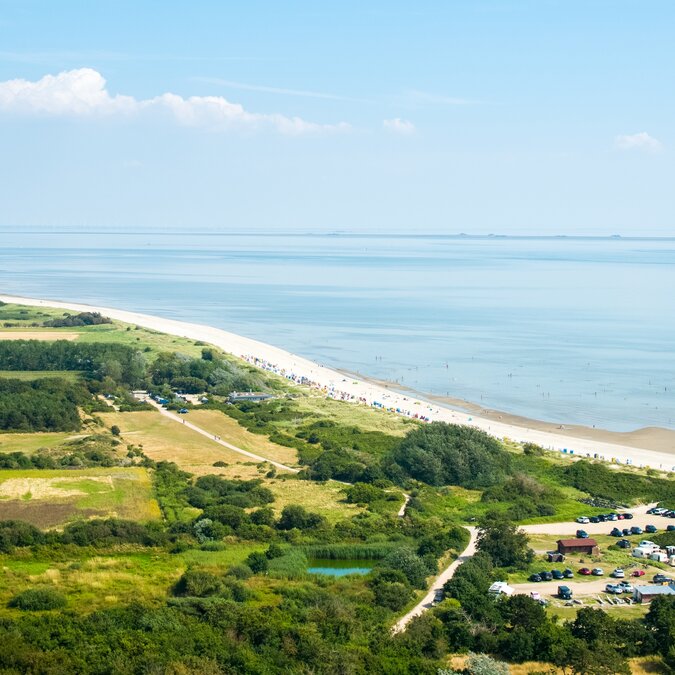 Vue aérienne du petit village de Nieblum sur l'île de Föhr avec ses champs verdoyants, ses maisons et la côte de la mer du Nord. | © shutterstock / 2509201019