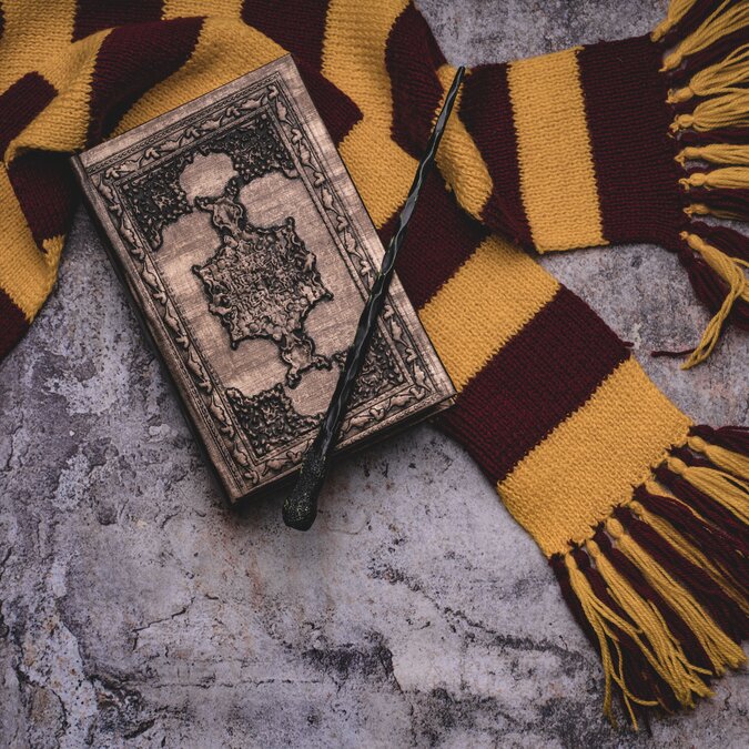 Themes of the magic school. Scarf, magic wand, spell book on a gray background | © Shutterstock 1564885576