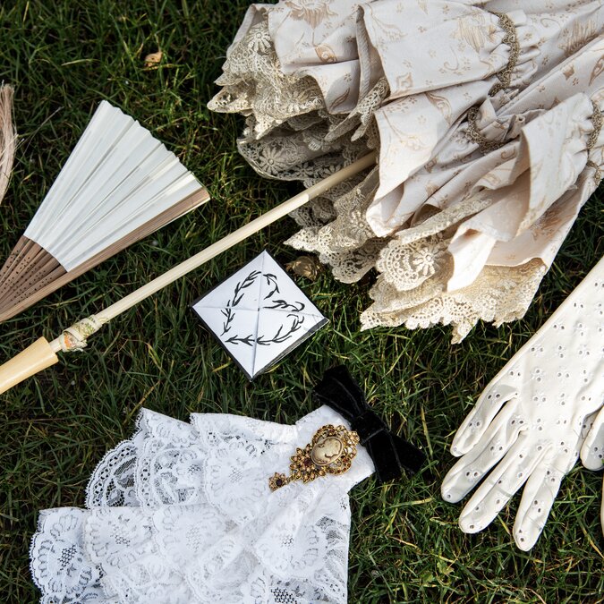 Vintagecore aesthetic. Set of accessories for women: lace parasol, ruffles, cameo brooch with bow, hand fan with tassels, broderie anglaise gloves. Love note painted in ink. | © Shutterstock_2704773479