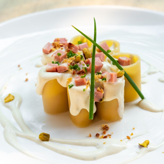 Paccheri italien pâtes fraîches traditionnelles avec mortadelle jambon bolognaise, fromage, crème, pistaches, belle garniture art plating professional chef fine dining food in natural back light,outdoor eating | © Shutterstock 1445388362